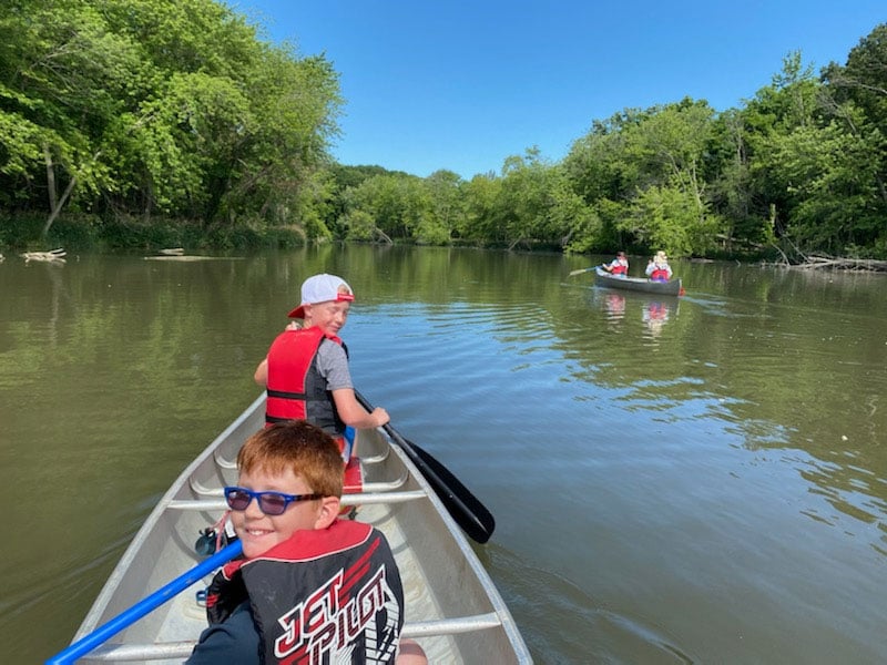 two boys on a canoe looking backwards at photographer