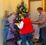 3 volunteers decorating a Christmas tree